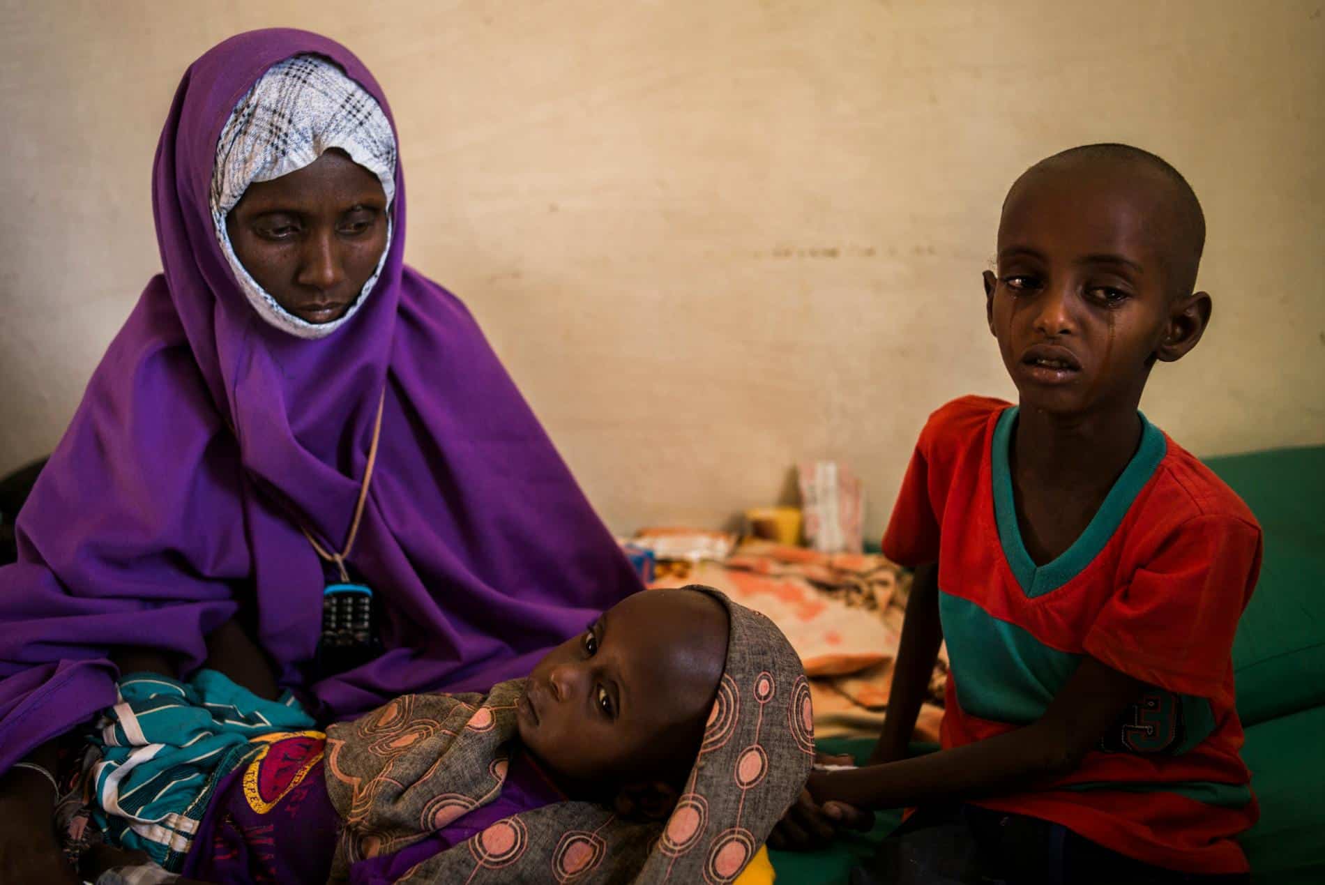 Sahro Mohamed Mumin holds her two-year-old son, Abdulrahman Mahamud, inside the health clinic in the Shada IDP camp. Abdulrahman was diagnosed with pneumonia and his brother Abullahi with bronchitis. Both also suffer from severe malnutrition. The family traveled for nearly 100 miles to reach the camp after they lost all their livestock. [Source: National Geographic]